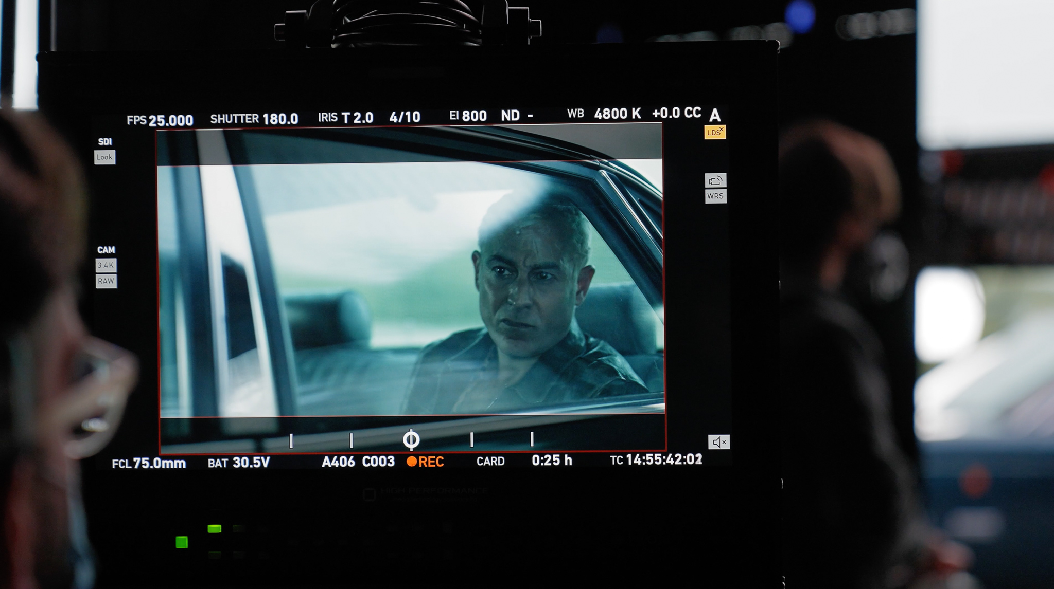 A man is seen on a video screen using virtual production equipment in a car.